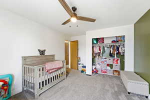Bedroom featuring carpet, a closet, a crib, and a ceiling fan