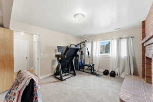 Exercise area with light carpet and a textured ceiling