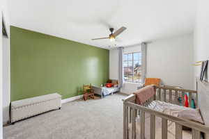 Bedroom with carpet, a ceiling fan, a nursery area, and radiator