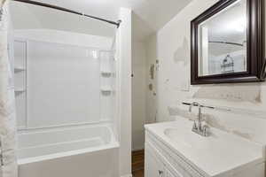 Bathroom featuring shower / tub combo with curtain, vanity, and dark wood-style flooring