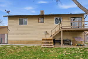 Back of property featuring a gate, a patio, a lawn, and a wooden deck