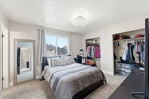 Bedroom with light colored carpet, a textured ceiling, and two closets