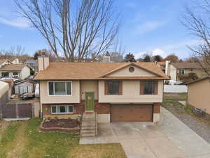 Raised ranch with a garage, a residential view, concrete driveway, and brick siding