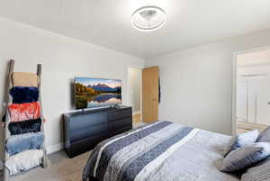 Bedroom with light colored carpet and a textured ceiling