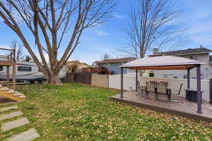 Fenced backyard featuring a gazebo, a deck, outdoor dining space, and a residential view