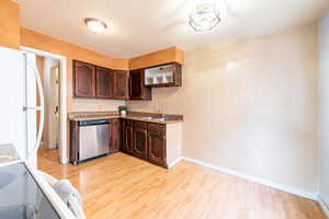 Kitchen with dark wood finish cabinets, freestanding refrigerator, light wood finished floors, stainless steel dishwasher, and range with electric stovetop