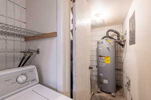 Laundry area with washer / dryer, electric water heater, concrete flooring, and electric panel