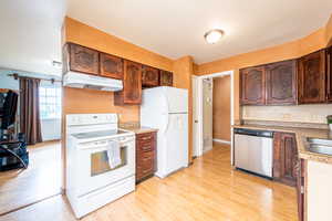 Kitchen with white appliances, light wood-style floors, and light countertops