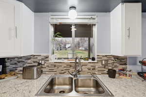 Kitchen featuring light stone countertops and white cabinetry