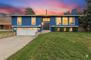 Split foyer home with an attached garage, concrete driveway, and a chimney