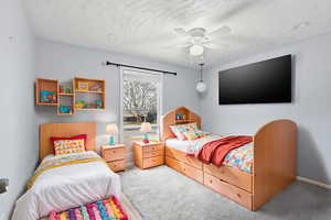 Carpeted bedroom featuring ceiling fan and a textured ceiling