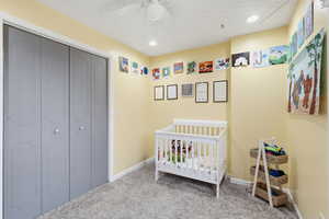 Carpeted bedroom with a nursery area, a closet, a ceiling fan, and recessed lighting