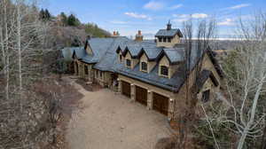 View of front of home featuring stone siding, stucco siding, decorative driveway, a high end roof, and covered porch