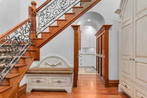 Staircase featuring arched walkways and hardwood / wood-style flooring
