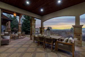 Patio terrace at dusk featuring an outdoor living / dining area, a patio area, and an outdoor stone fireplace