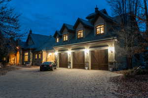 View of front of house with stone siding, decorative driveway, and a high end roof