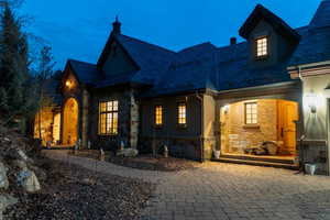 Back of property featuring a high end roof and stone siding