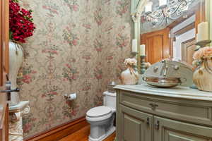 Bathroom featuring wallpapered walls, vanity, and wood finished floors