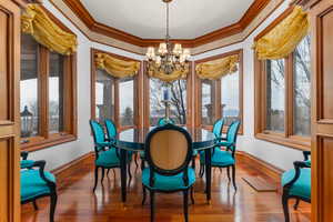 Dining area featuring wood-type flooring, hanging lights, ornamental molding, and plenty of natural light