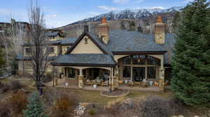 Rear view of property featuring a high end roof, a mountain view, stucco siding, a patio area, and a chimney