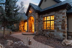 Exterior entry at dusk with stone siding and a high end roof