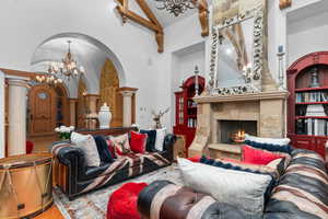 Living area with suspended lighting, vaulted ceiling, arched walkways, and a fireplace