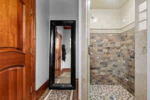 Full bathroom featuring a stall shower and baseboards