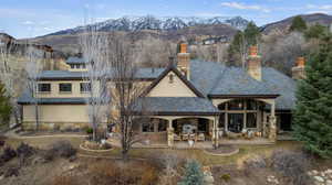 Back of property with a mountain view, stucco siding, a high end roof, and a chimney