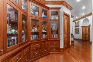 Detailed view of crown molding, wood finished floors, and recessed lighting