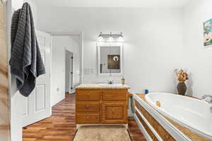 Full bathroom with vanity, light wood-type flooring, and a garden tub
