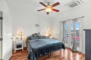 Bedroom with cooling unit, ceiling fan, wood finished floors, and access to exterior