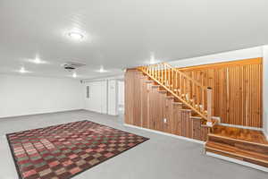 Finished below grade area with wood walls, cooling unit, and electric panel