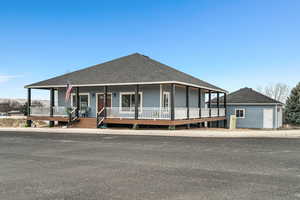 Farmhouse inspired home featuring roof with shingles and a porch
