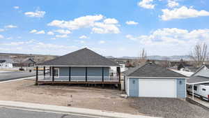 View of front of house featuring a shingled roof, a porch, a mountain view, a detached garage, and a residential view