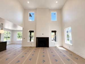 Vaulted ceiling great room featuring a fireplace, multiple windows, recessed lighting, and a partial view of a kitchen island with a pendant light fixture