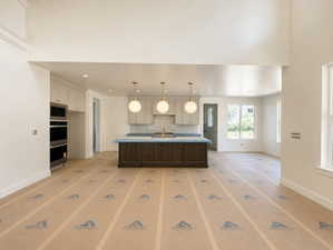 Open-concept kitchen featuring light-toned cabinetry, a dark wood-finish island, and stainless steel built-in appliances