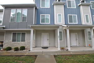 Doorway to property featuring a porch, stone siding, and board and batten siding