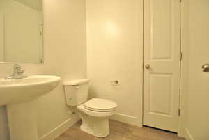Half Bathroom featuring toilet and light wood-style flooring
