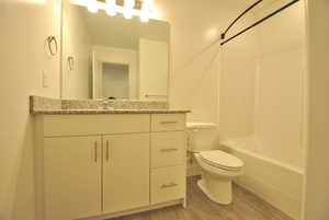 Full bath featuring vanity, bathing tub / shower combination, and light wood-style flooring