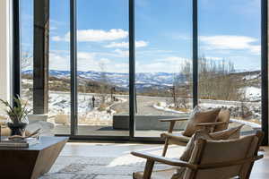 Sitting room with a mountain view, wood finished floors, and expansive windows