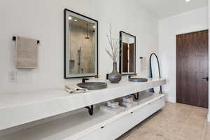 Full bathroom featuring double vanity, recessed lighting, a tile shower, and light tile patterned flooring