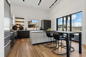 Kitchen featuring open shelves, modern cabinets, high end appliances, light wood-style flooring, and a breakfast bar area