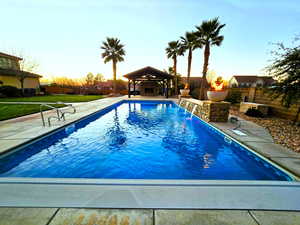 Pool at dusk featuring a fenced backyard and a patio