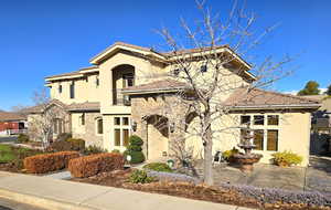 Mediterranean / spanish-style house featuring a tiled roof, stucco siding, stone siding, and a balcony