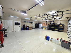 Garage featuring freestanding refrigerator and a garage door opener