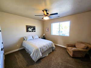 Bedroom with a ceiling fan and dark carpet