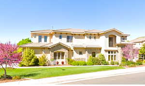 Mediterranean / spanish home featuring stone siding, a front yard, stucco siding, and a tiled roof