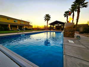 Pool at dusk with a patio area, an outdoor pool, and a fenced backyard
