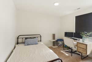 Bedroom with light carpet and a desk