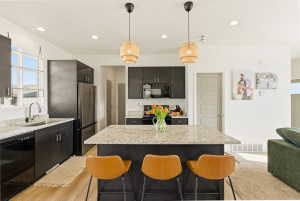 Kitchen with black appliances, hanging light fixtures, and light stone counters